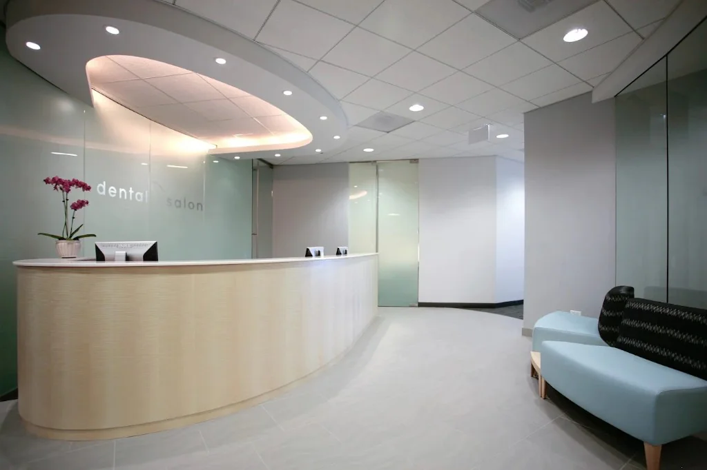 Dental Salon reception area with curved wood desk, frosted glass branding, and bright modern interior.